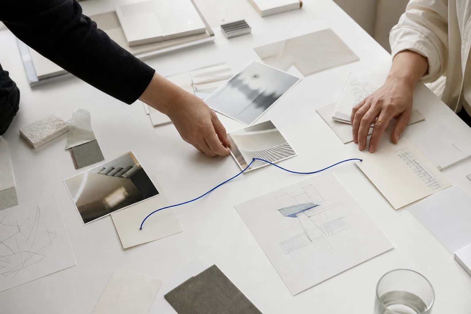 Two collaborators connect photographs and diagrams across a bright shared table.