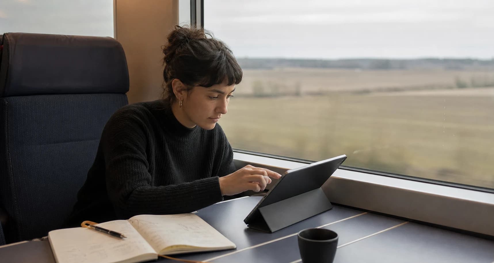 A researcher working from a tablet beside a train window.